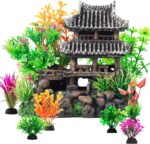 A gray resin castle aquarium decoration with arched entrances, surrounded by eight green and purple artificial aquarium plant
