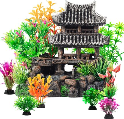 A gray resin castle aquarium decoration with arched entrances, surrounded by eight green and purple artificial aquarium plant