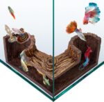 A dark brown, textured FISHNOSH aquarium cave, designed to look like natural driftwood, placed in a fish tank corner.