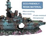 A detailed blue resin sunken ship decoration positioned within a vibrant aquarium, surrounded by green aquatic plants.