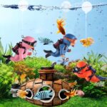 Two pink floating diver ornaments with tiny oxygen tanks and cameras, submerged in a clear fish tank with bubbles.